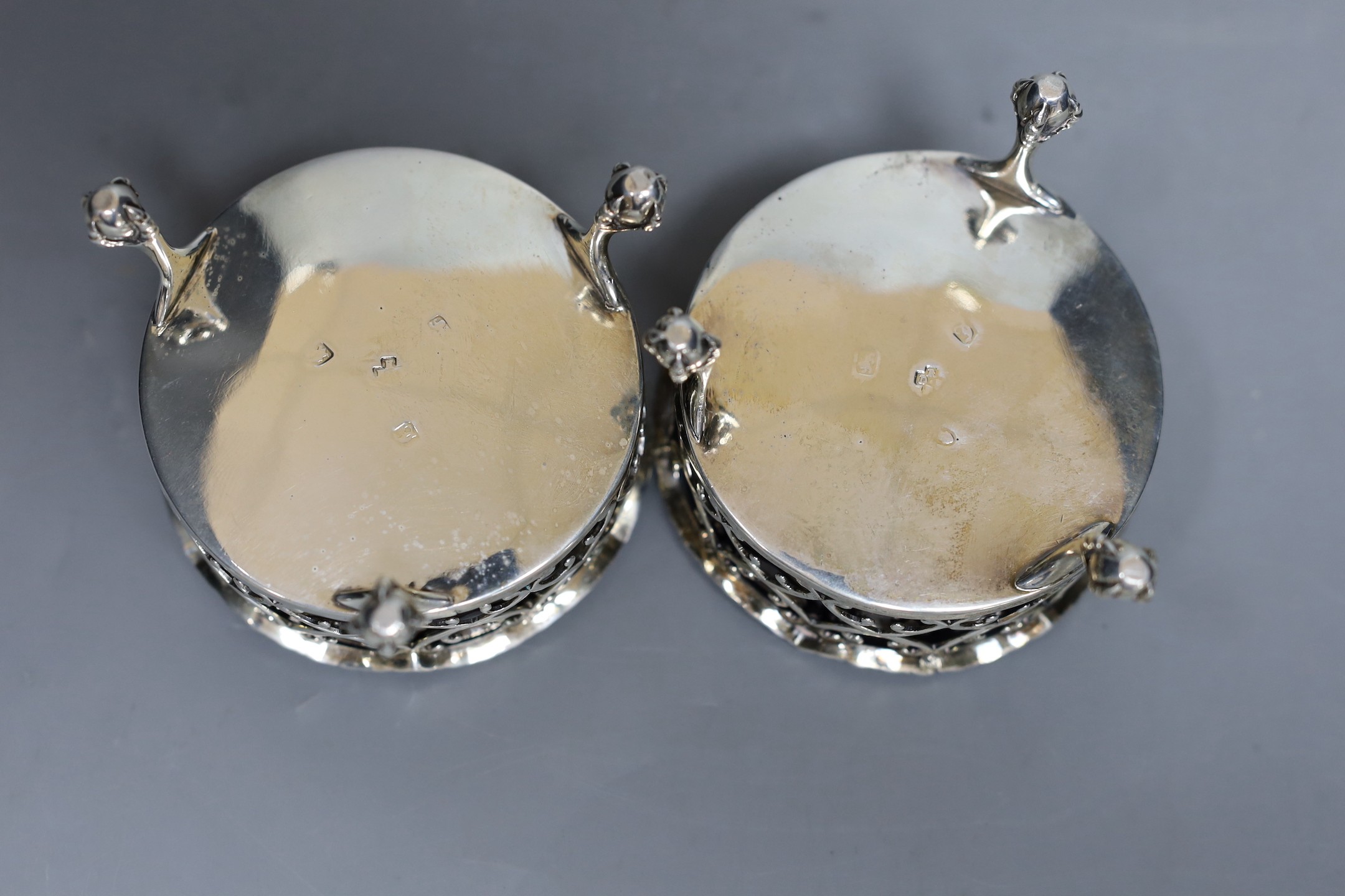 A pair of George III pierced silver circular salts, London, 1764, 79mm, with two associated spoons.